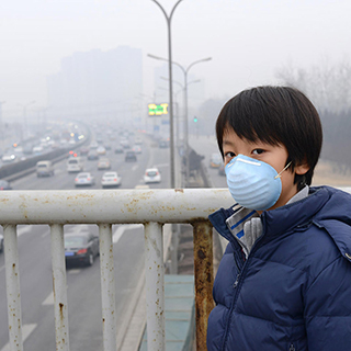 boy wearing face mask with foggy sky and traffic in the background