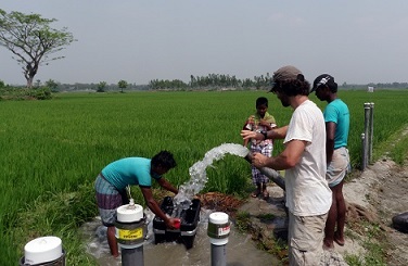 Figure 1: Trainee Mason Stahl and students at the Bangladesh University of Engineering and Technology measure the pump rate of an irrigation well, which helps control the direction of groundwater flow in the area close to the study pond.