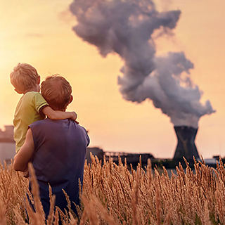 man holding child while watching smoke rise from power plant
