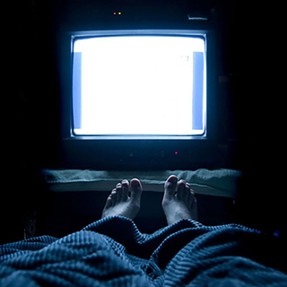 person watching TV while laying in bed
