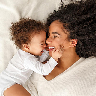 woman and baby laying in bed and smiling