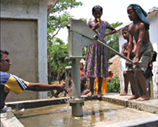 image of people pumping water from a hand pumped well.