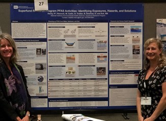 Michelle Heacock, Ph.D., and Heather Henry, Ph.D., standing in front of their poster